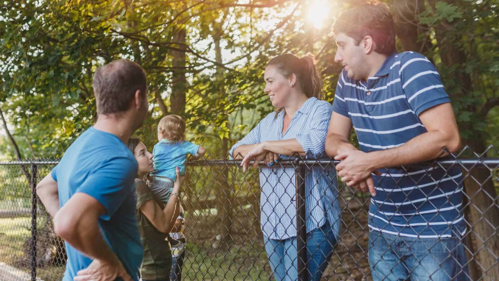 Family enjoying quality time outdoors near a fence in a lush, green setting.