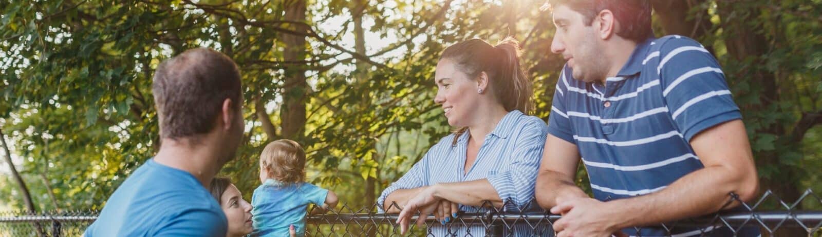 Family enjoying quality time outdoors near a fence in a lush, green setting.