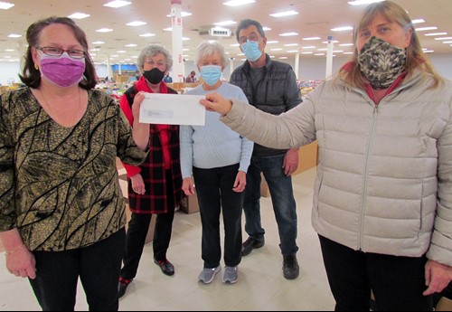 Shows 2 people in a store holding a cheque from McDougall Energy and 3 people behind them