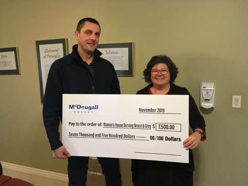 Shows 2 people holding a large cheque from McDougall Energy