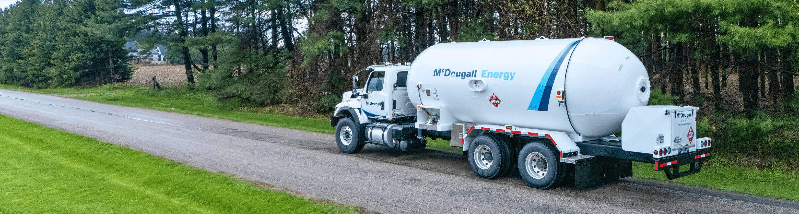 Thermal oil tanker truck on rural road, McDougall Energy fuel delivery service.