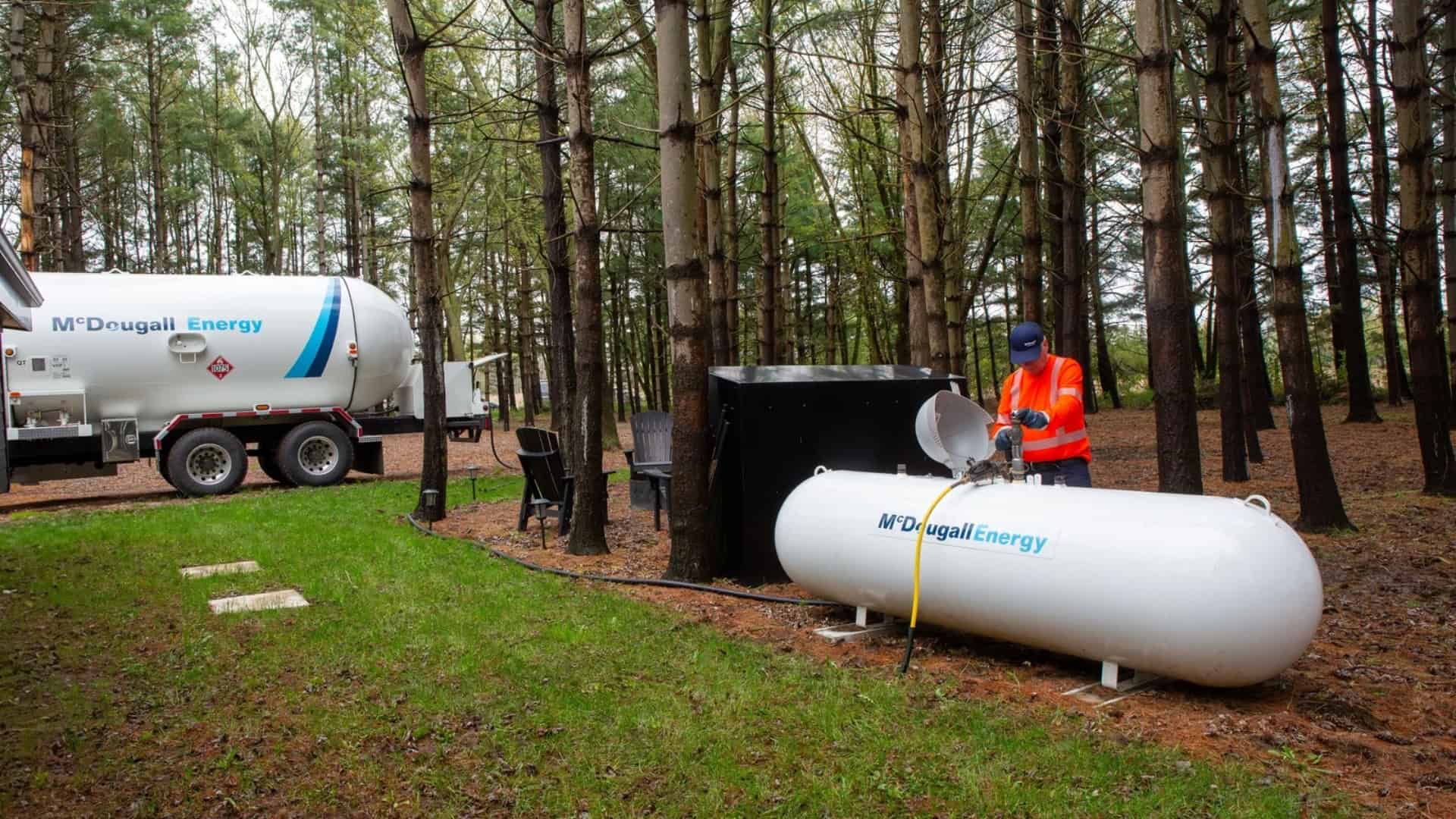 McDougall Energy Technician filling a large propane tank at a residence in Ontario with a wooded background.