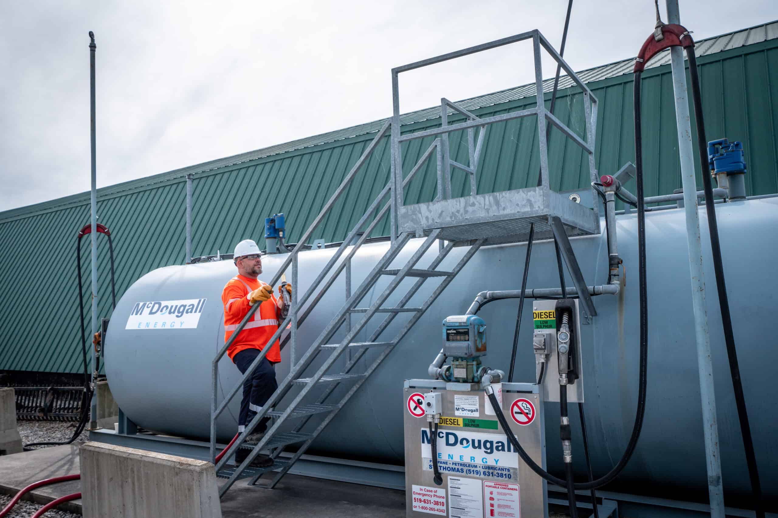 Propane storage tank at McDougall Energy fueling station with technician inspecting safety controls.