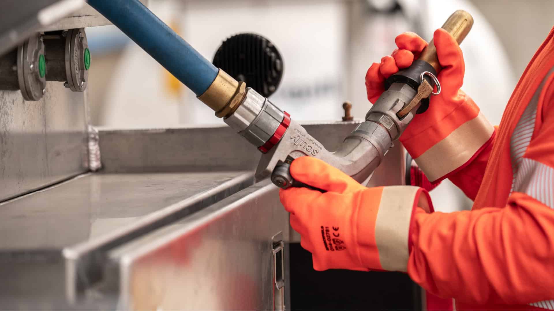 Fuel technician unloading fuel hose from a McDougall Energy branded fuel truck.