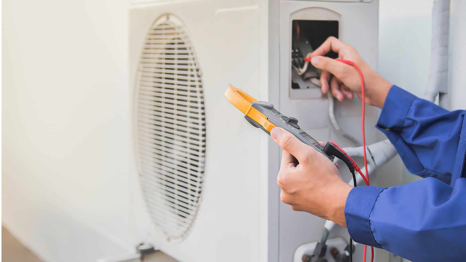 Technician testing HVAC system with multimeter in a residential setting.