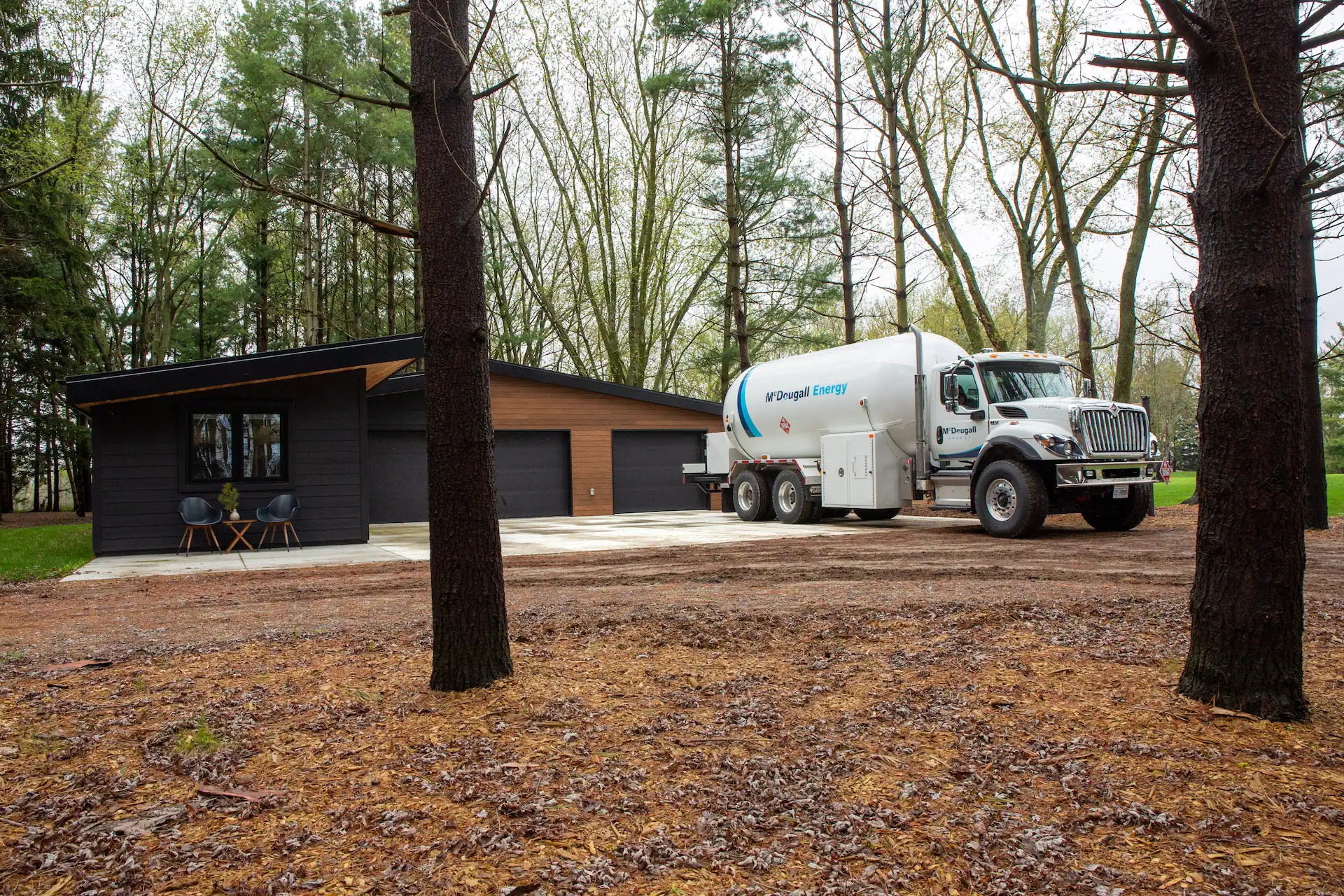 Fuel delivery truck at a modern home in Ontario in a wooded area, representing McDougall Energy's residential propane delivery service.