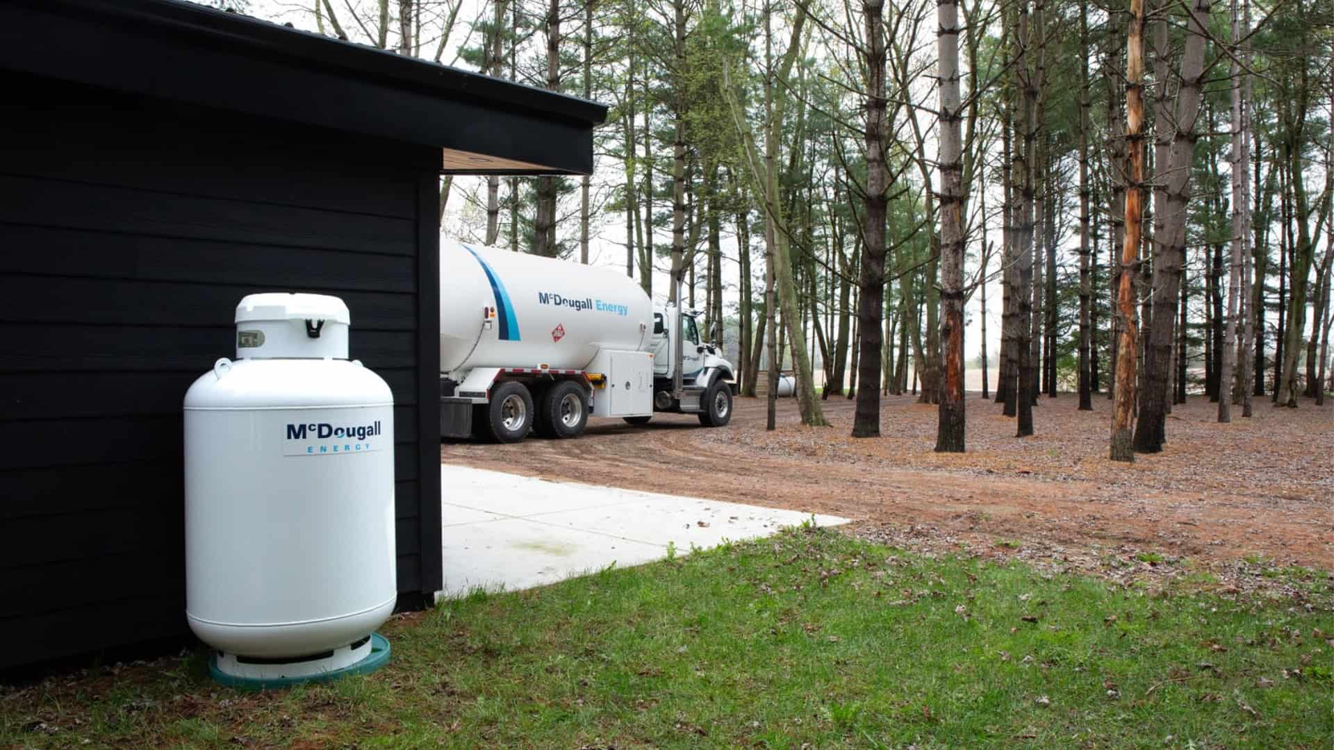 McDougall Energy Propane truck making a propane delivery to a residence in Ontario surrounded by lush woods.