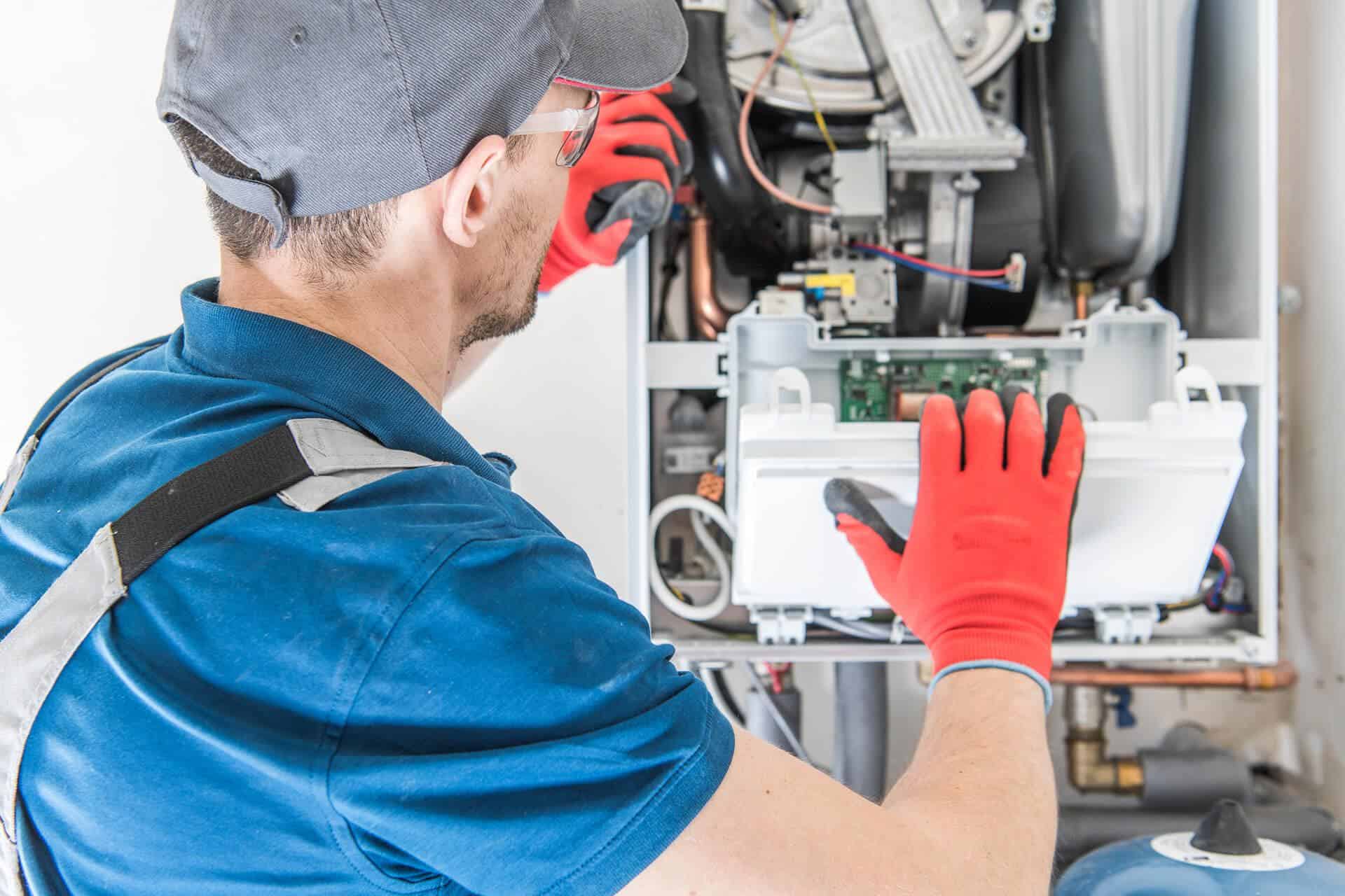 High-efficiency HVAC technician repairing heating system, as part of the annual HVAC service plan from McDougall Energy.
