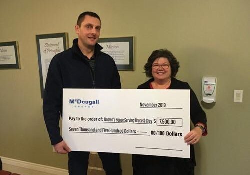 Shows 2 people holding a large cheque from McDougall Energy